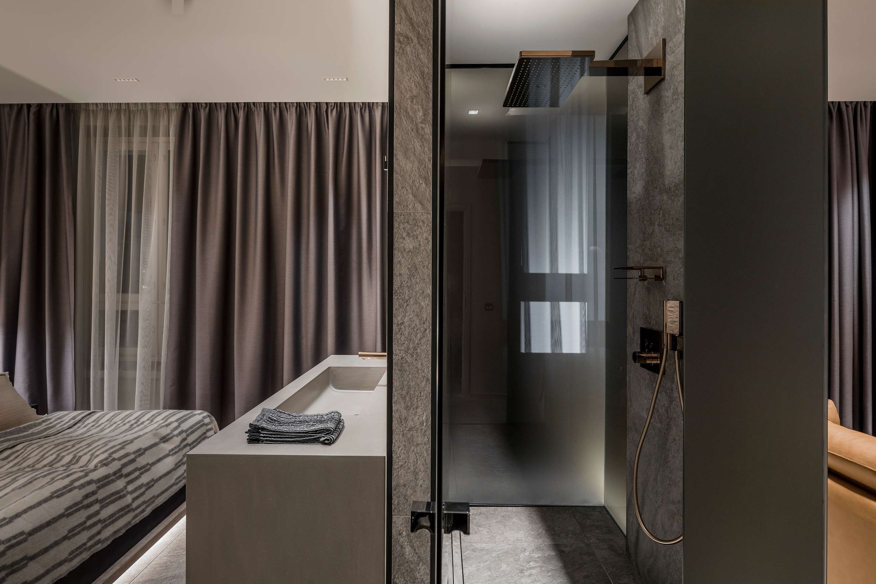 A modern bathroom with a glass shower enclosure, a built-in sink, and a vanity with a towel.