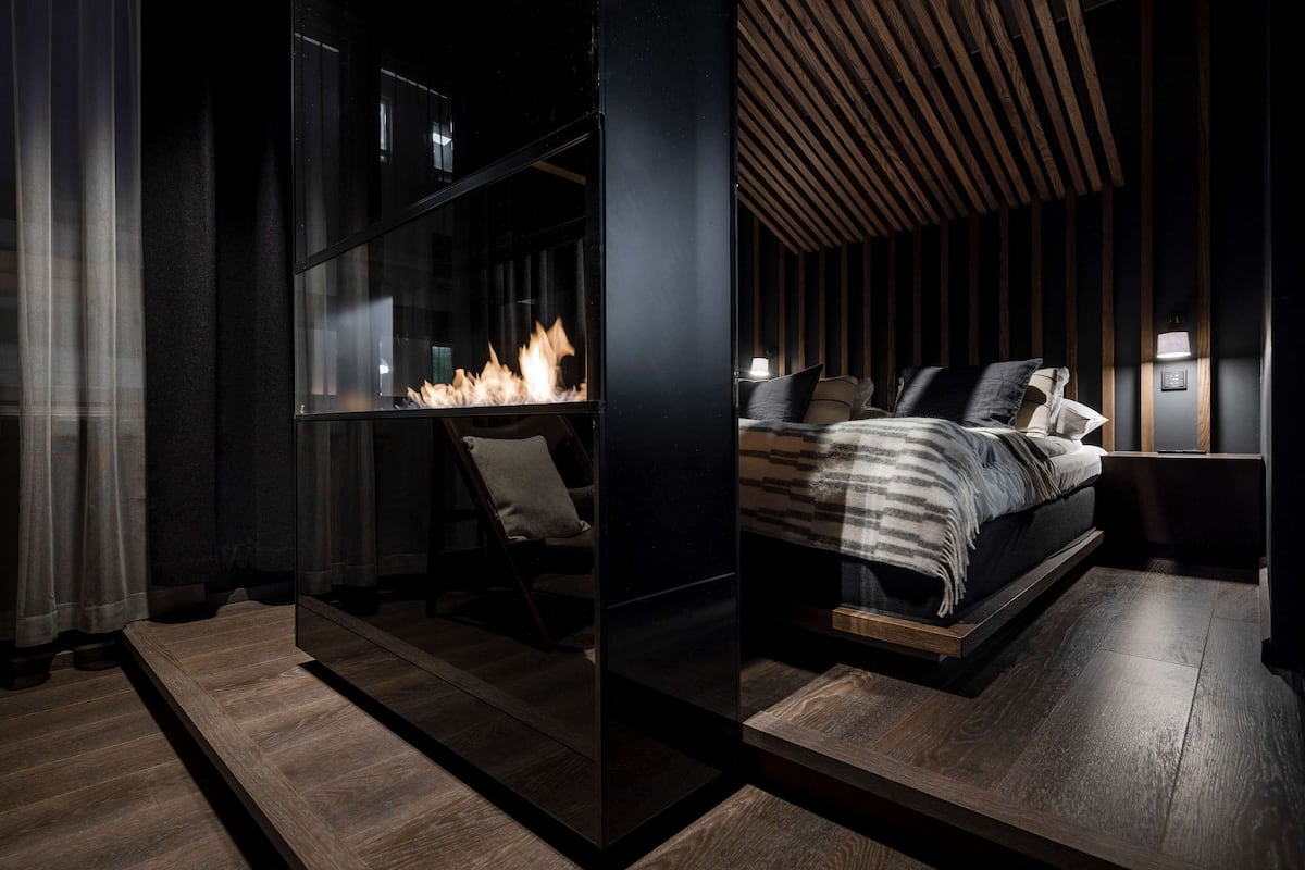 Une chambre à coucher moderne avec un lit, des tables de chevet et une cheminée.