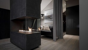 Een moderne woonkamer met een inbouwkachel, een bank en een eigentijds kunstwerk aan de muur.