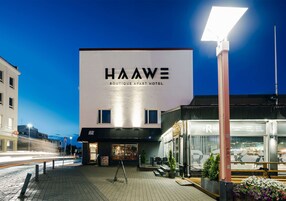 Exterior del Hotel Aparto Boutique Hawe, con vista despejada de la entrada, un paseo empedrado y una calle al fondo.