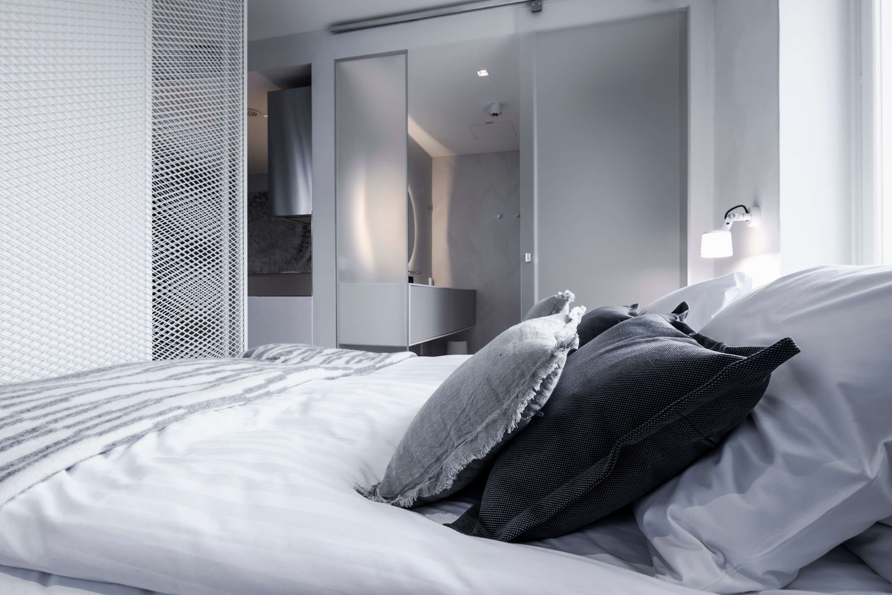Une chambre d’hôtel moderne avec un lit bien fait, un grand miroir et un dressing.