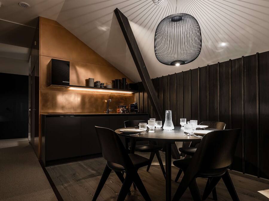 A modern kitchen with a built-in island, dark wood paneling, and a unique pendant light.