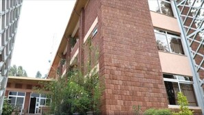 A multi-story building with a brick facade, balconies, and a metal structure on the left.