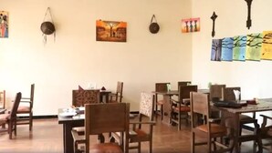 A dining area with wooden tables and chairs, artwork on the walls, and a hanging light fixture.