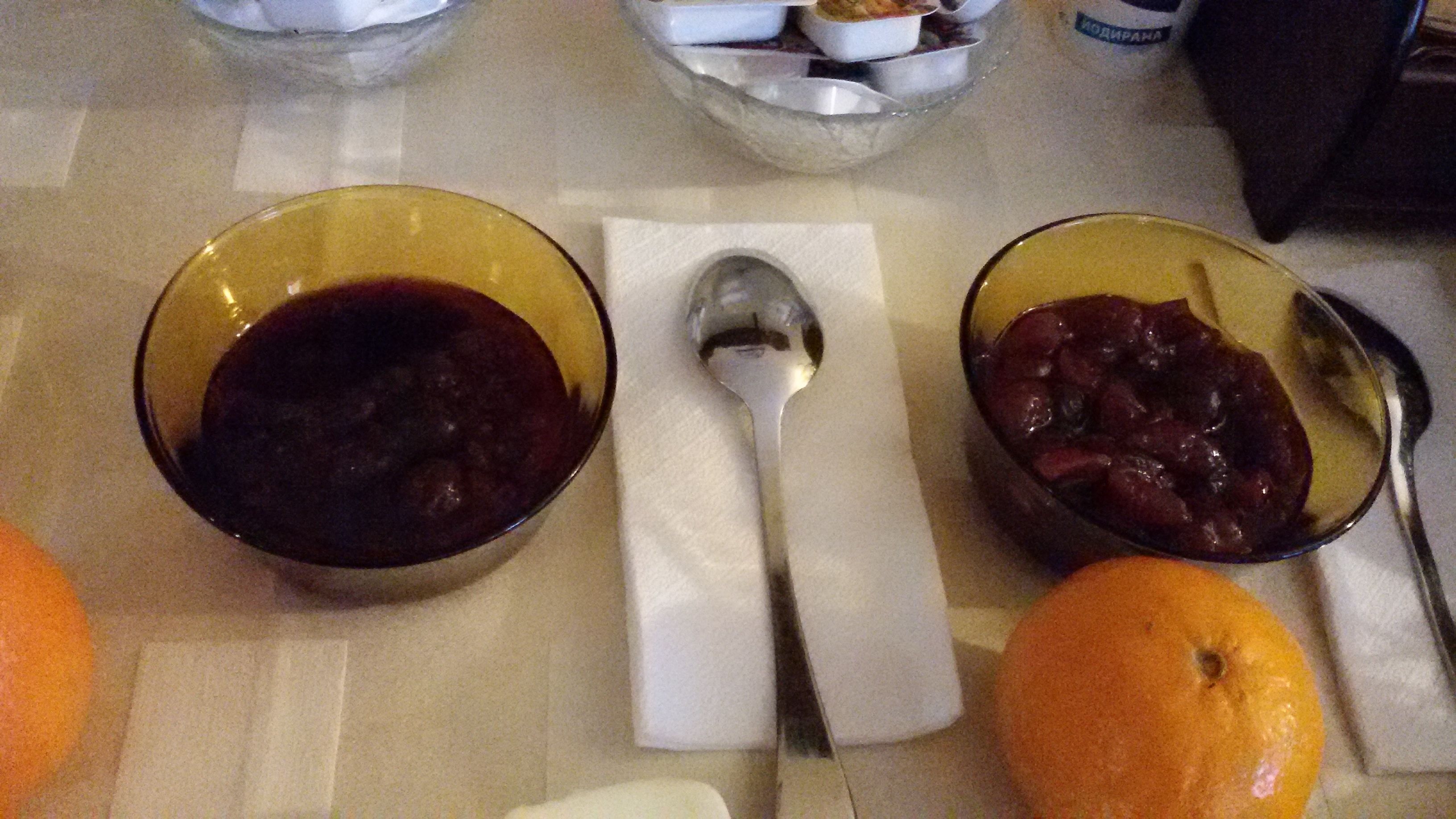 Two bowls of fruit on a table with a spoon and a napkin.