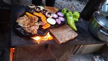 A grill with various foods including mushrooms, sausages, and vegetables.