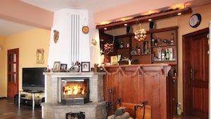 A cozy living room with a fireplace, wooden shelves, and a television. - Ilinden (Bansko)