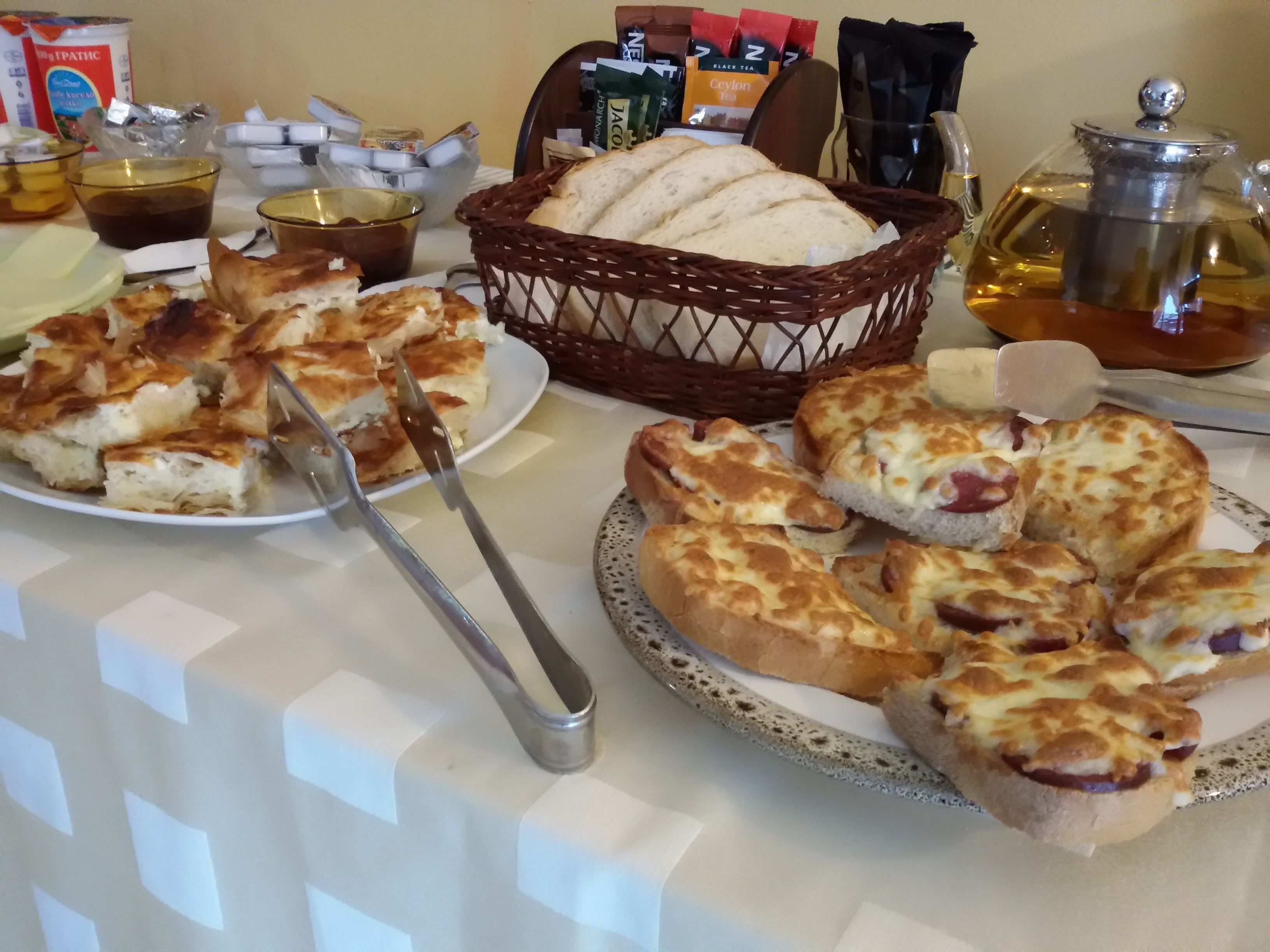 A table with various food items, including bread and pastries, and a basket of bread.