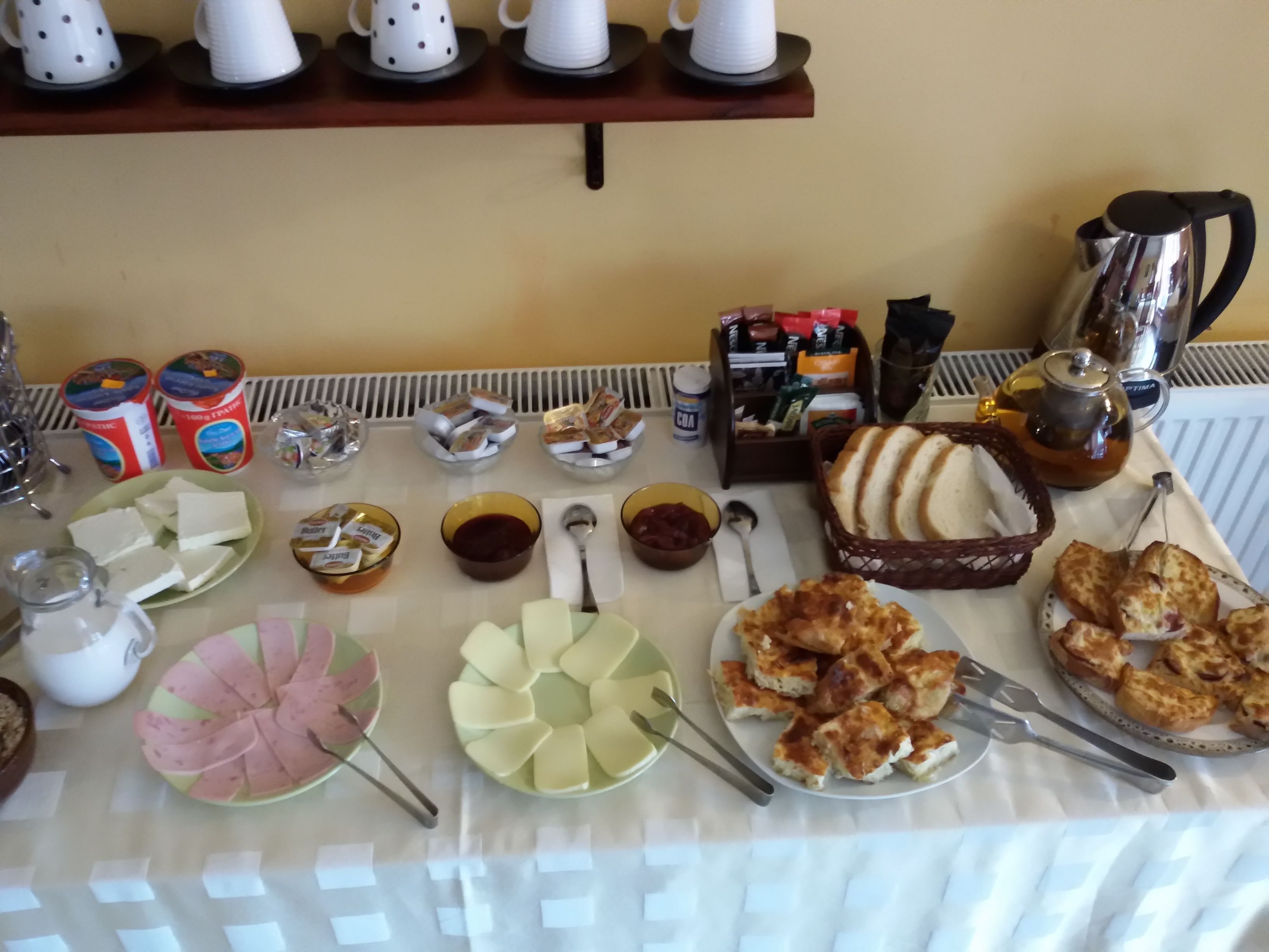 A breakfast buffet with various food items, condiments, and beverages.