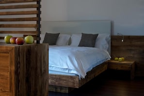A wooden bed with white bedding, a nightstand with a lamp, and apples on the side table. - Agriturismo Florandonole (Fai della Paganella)