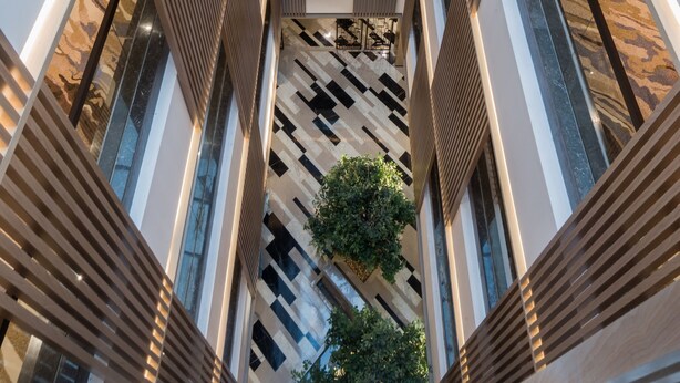 A modern interior with a central atrium, multiple floors, and a patterned floor. - Boudl Al Corniche (Dammam)