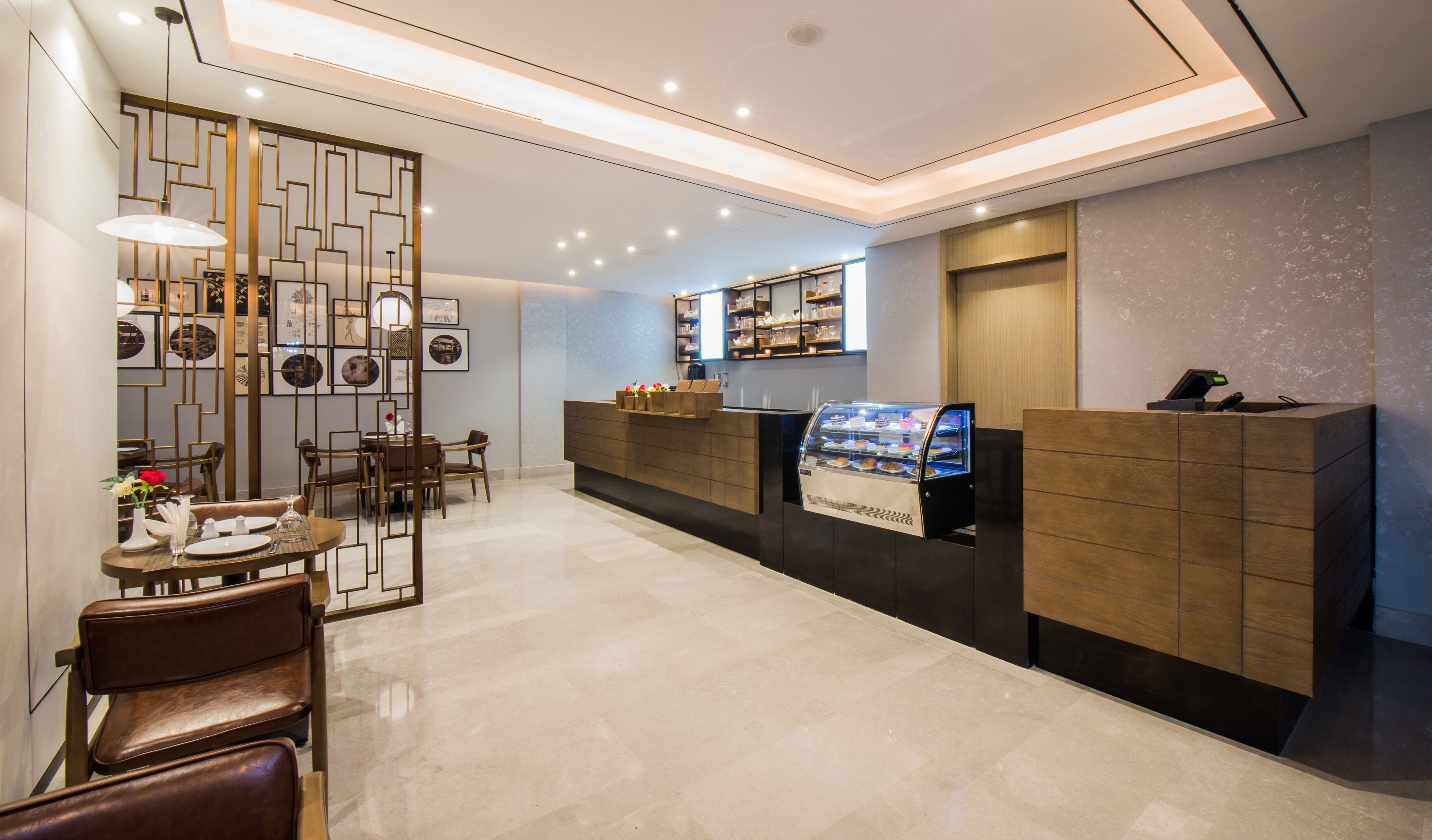 A modern hotel lobby with a reception desk, seating area, and a display case.
