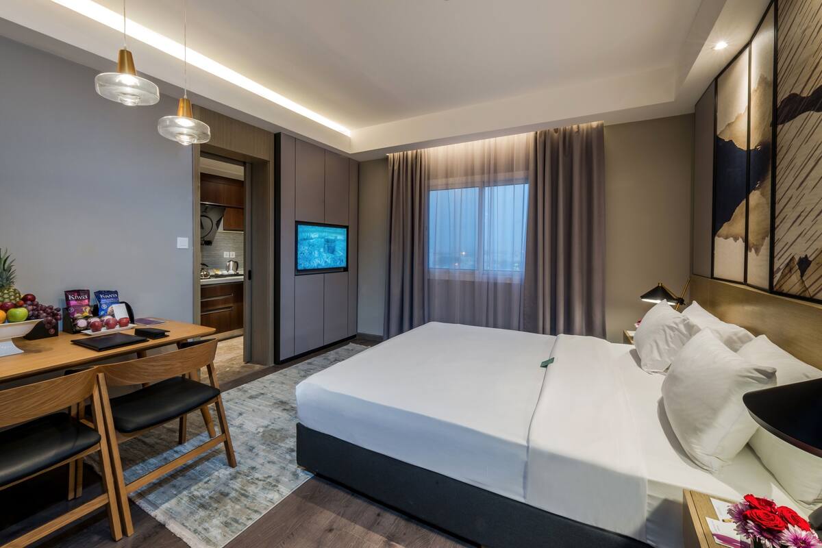 A modern hotel room with a bed, desk, chair, and a television.