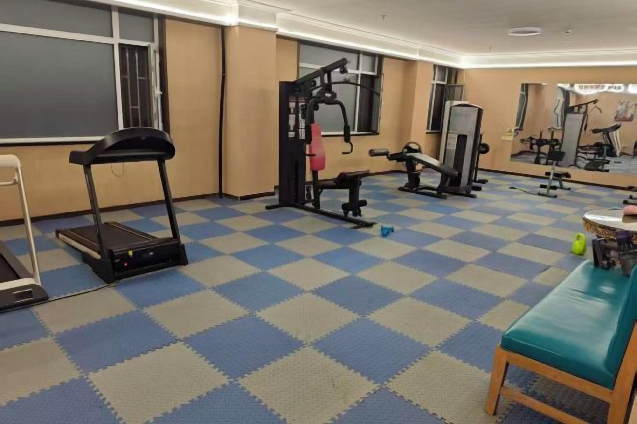 A gym with exercise equipment, a treadmill, and a mirrored wall.