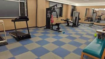 A gym with exercise equipment, a treadmill, and a mirrored wall.