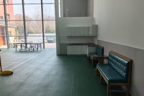 Una habitación con un banco, una mesa y un área de kitchenette.