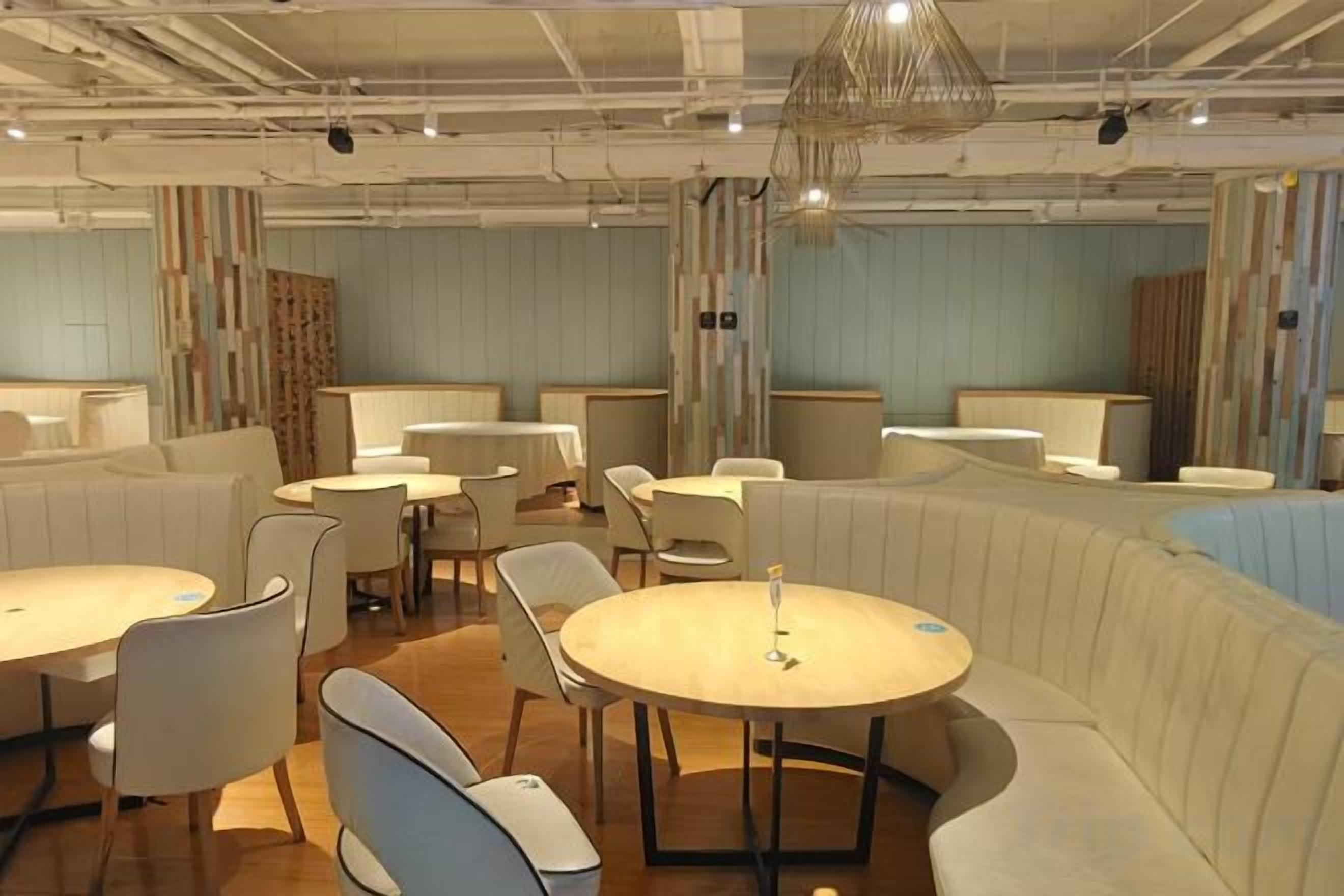 Un interior de restaurante moderno con mesas redondas, asientos acolchados y un diseño contemporáneo.