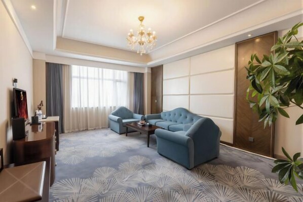 A modern living room with a sofa, armchair, coffee table, and a chandelier. - Danube International Hotel (Qingdao)