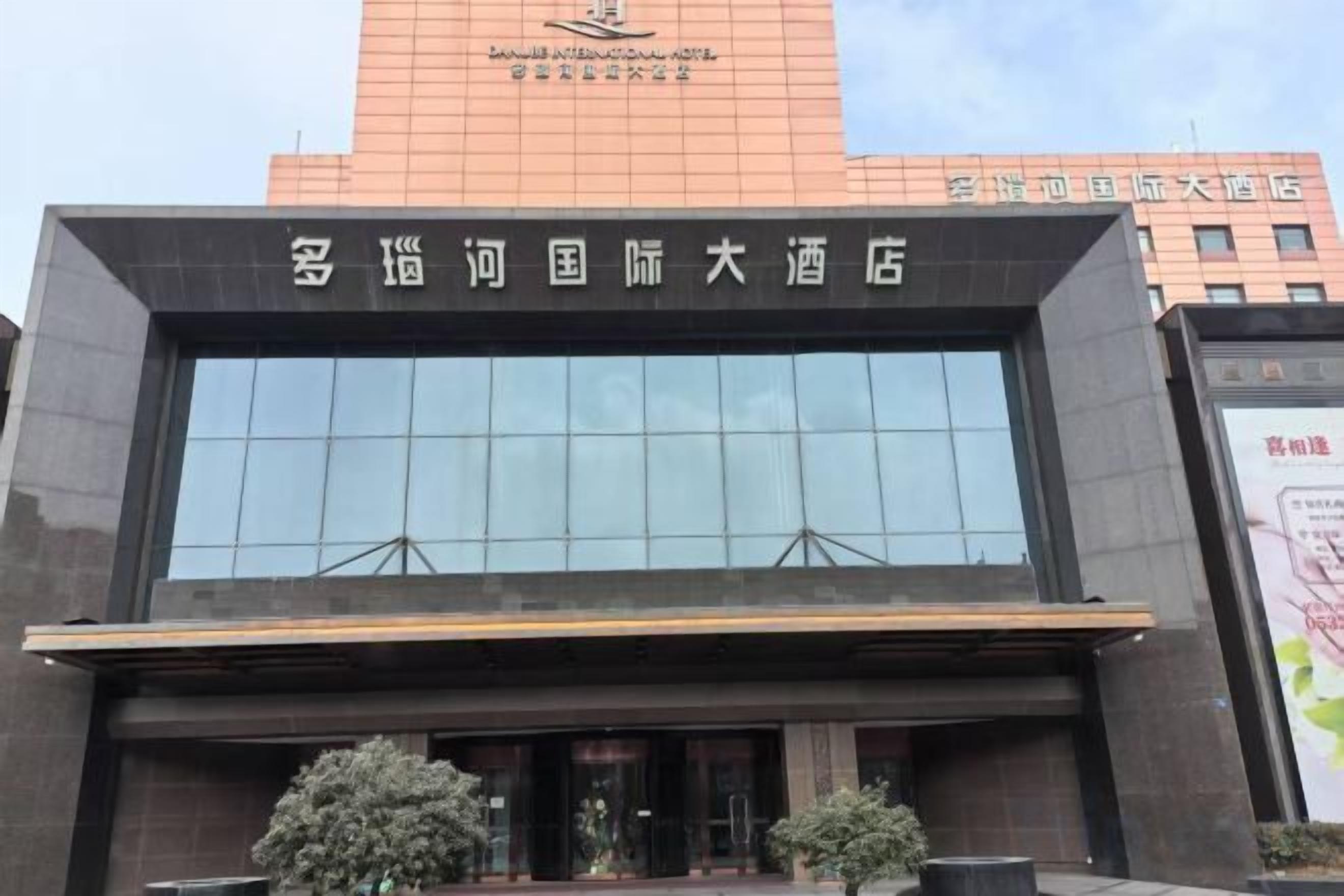 A modern hotel building with a large glass facade and a prominent sign above the entrance.