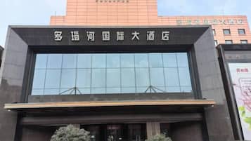 A modern hotel building with a large glass facade and a prominent sign above the entrance.