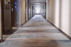 A long, narrow hallway with doors on both sides, leading to rooms. - Danube International Hotel (Qingdao)