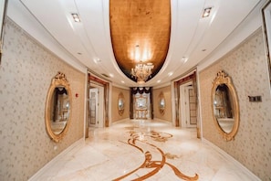 A luxurious hallway with ornate mirrors, a grand chandelier, and a marble floor. - Danube International Hotel (Qingdao)