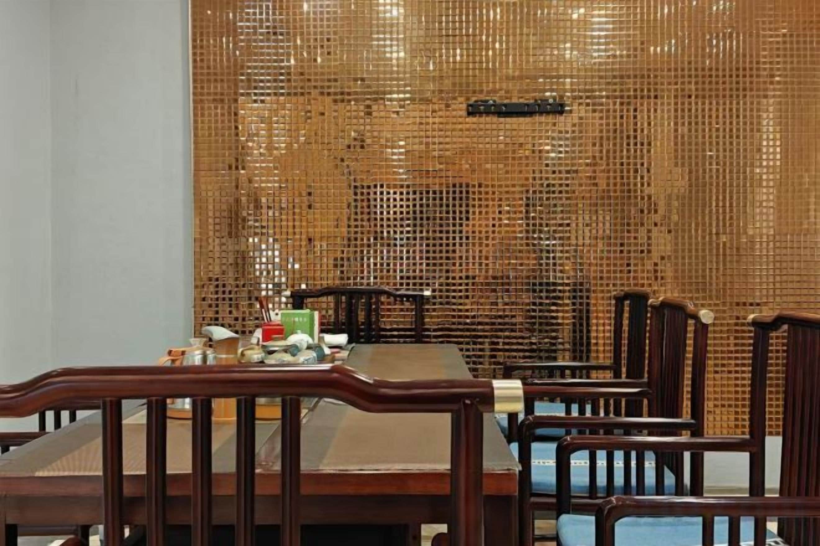 A dining area with a bamboo wall, wooden chairs, and a table set with dishes.