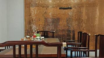 A dining area with a bamboo wall, wooden chairs, and a table set with dishes.