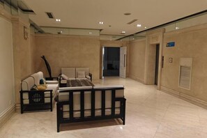 A spacious hotel lobby with a seating area, a reception desk, and a door leading to another room. - Danube International Hotel (Qingdao)