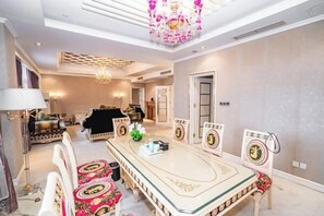 Una sala de estar amplia con una mesa de centro grande y ornamentada, elegantes sillas y una araña.