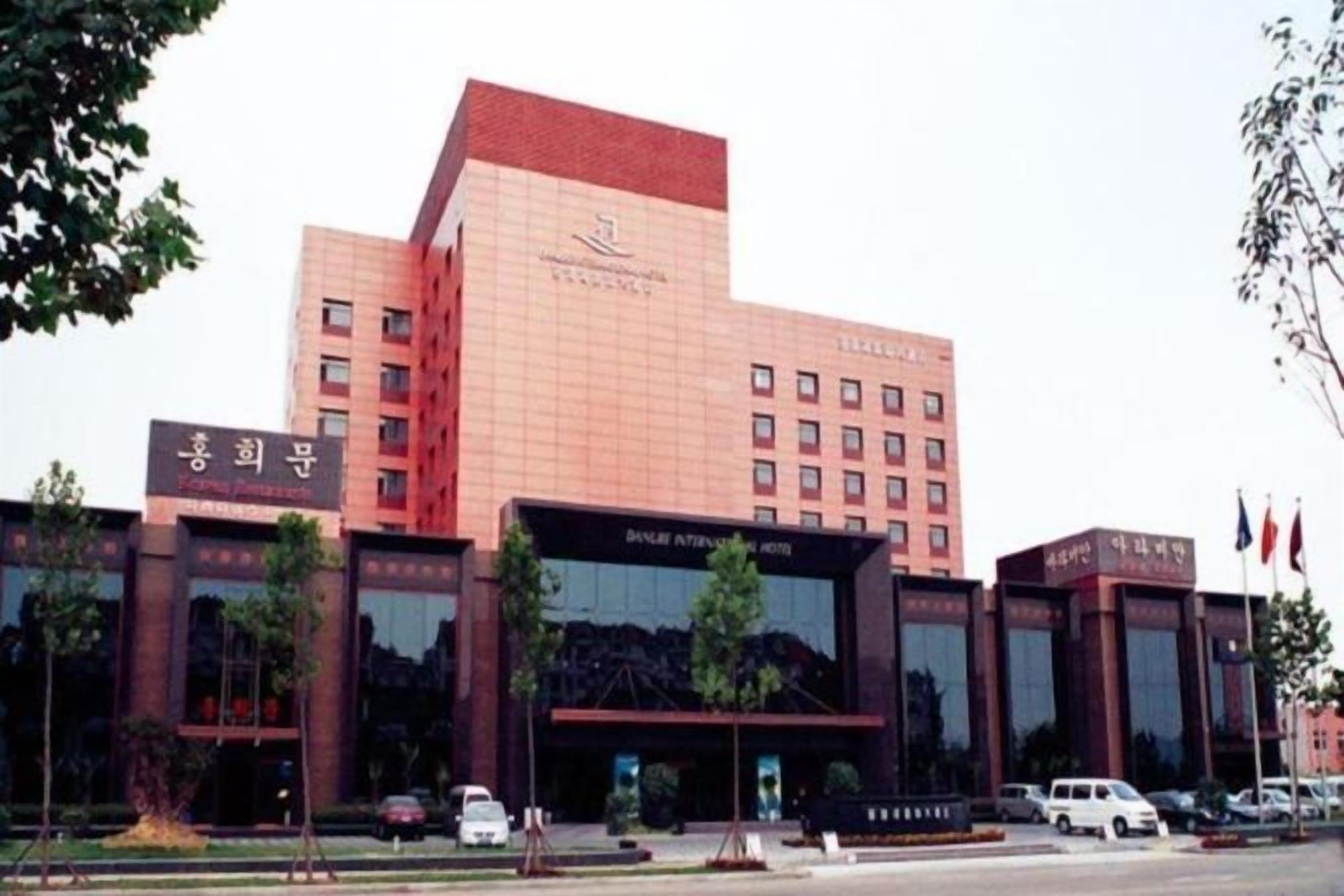 A multi-story hotel with a prominent red-brick facade, large glass windows, and a modern entrance.
