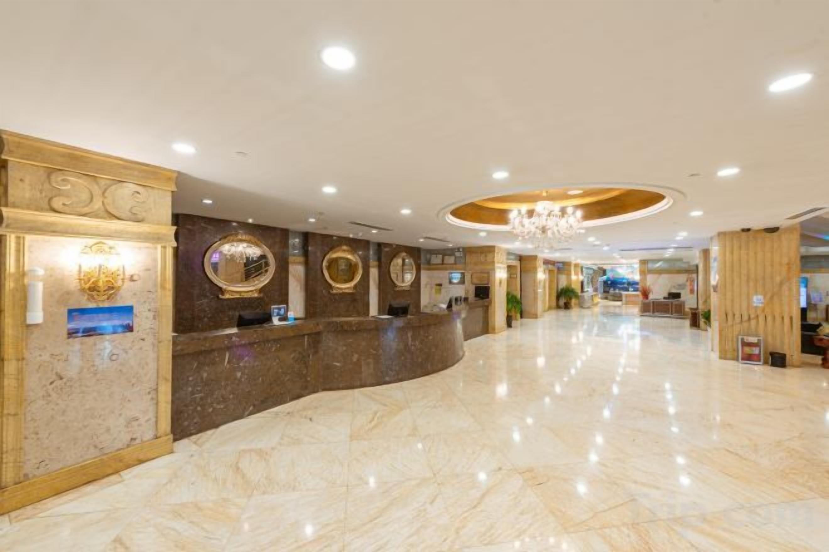 A hotel lobby with a marble floor, reception desk, and a chandelier.