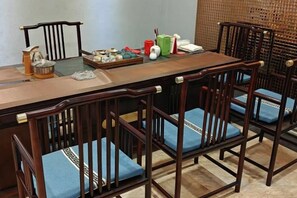 A dining area with a long wooden table and six wooden chairs with blue cushions. - Danube International Hotel (Qingdao)