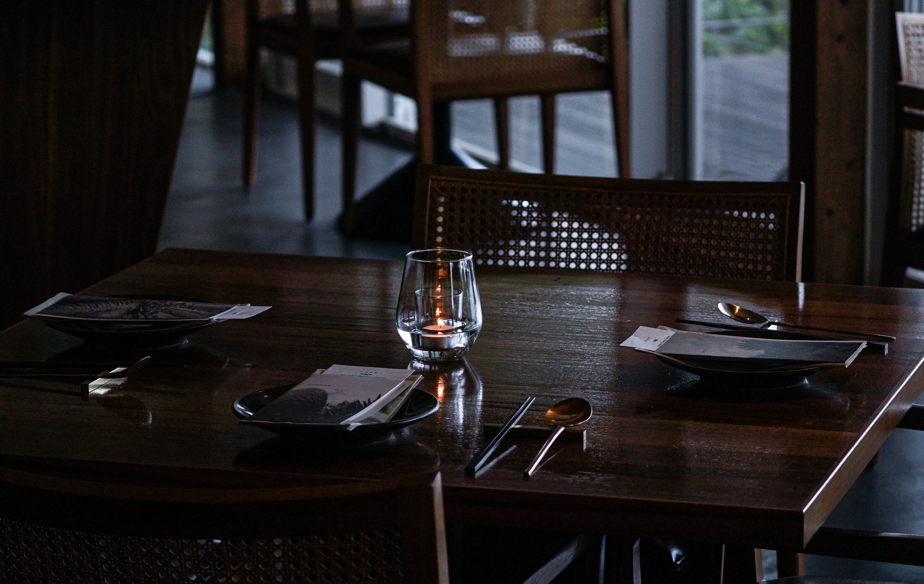 A dining table set with plates, cutlery, and a candle.