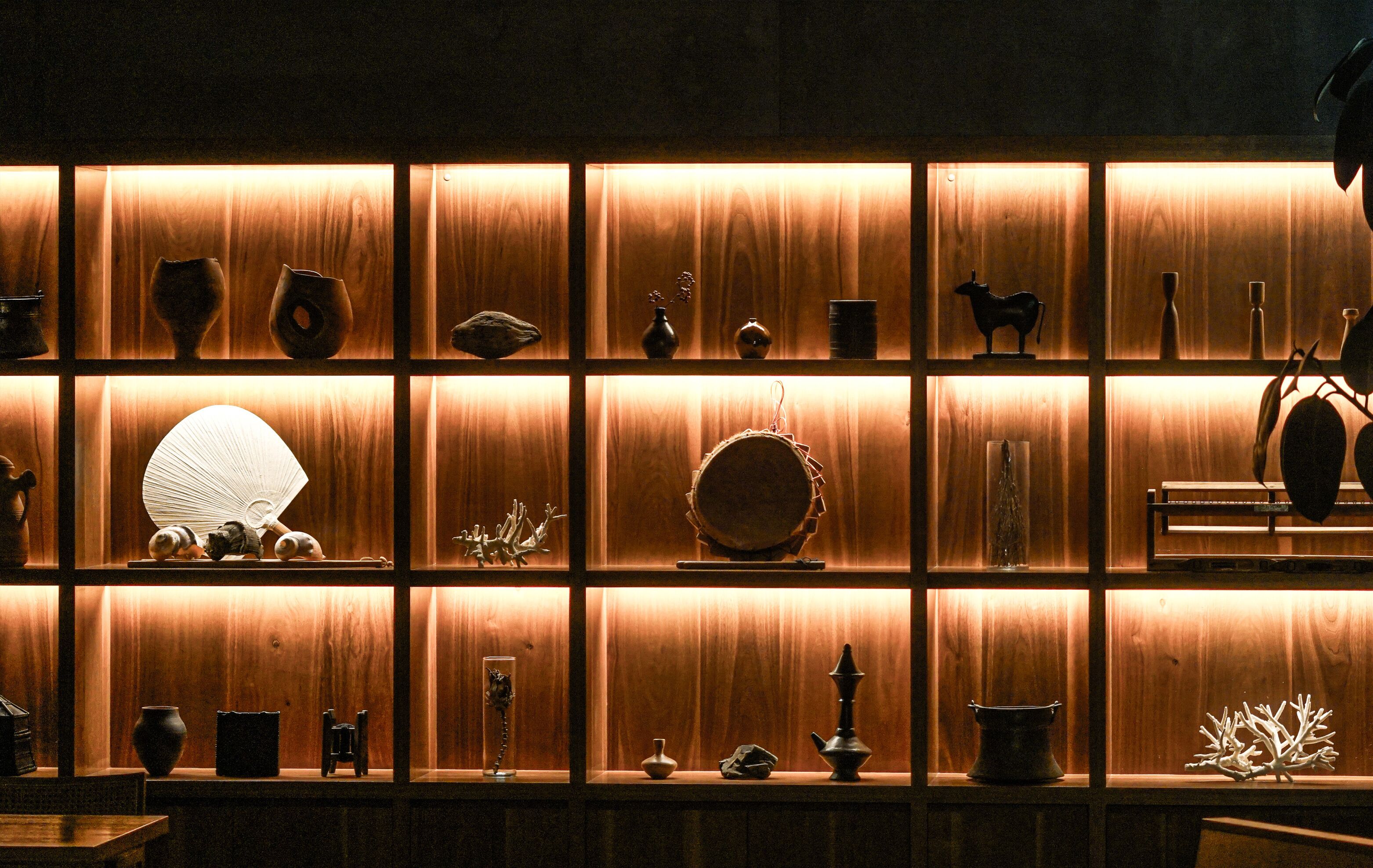 Un mur recouvert d’étagères où sont exposés divers objets décoratifs et meubles.
