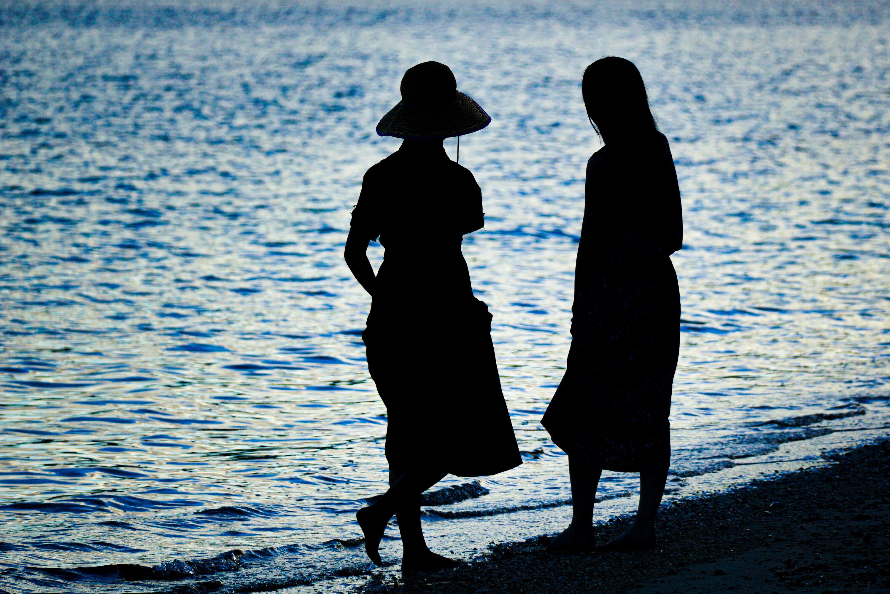 Dos siluetas de personas caminando por la playa.