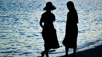 Dos siluetas de personas caminando por la playa.