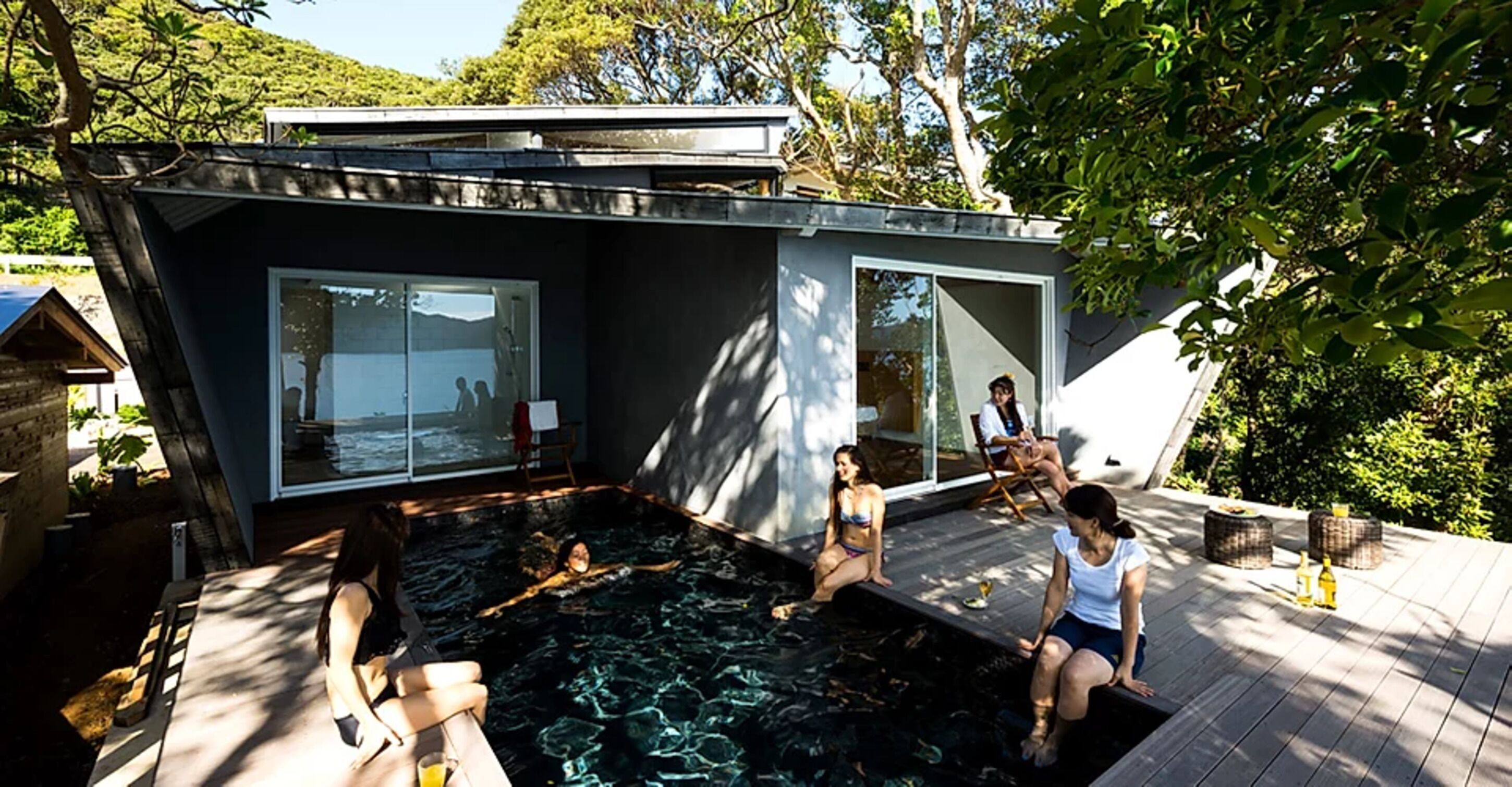 A modern house with a swimming pool, large windows, and a deck area.