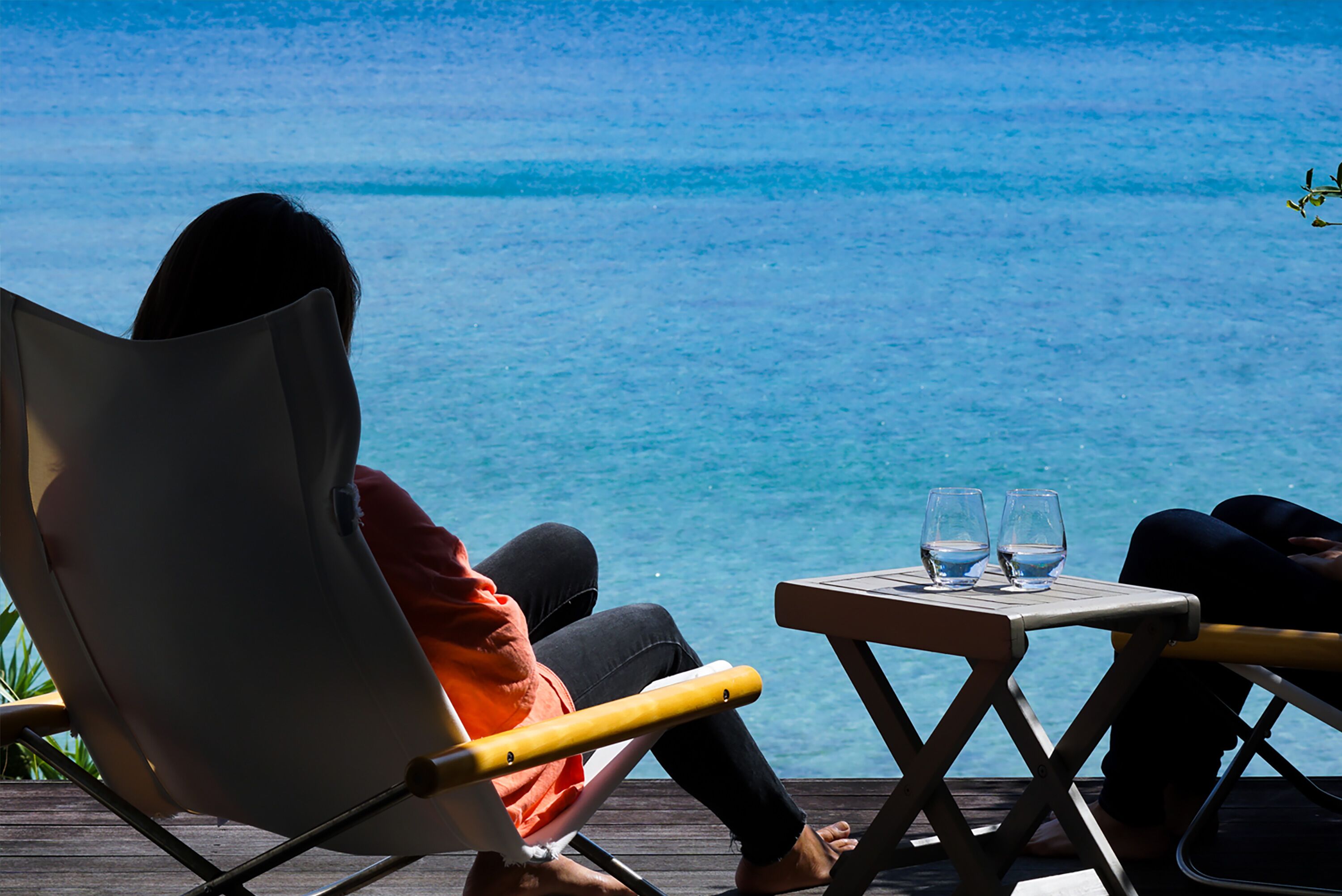 A person relaxing in a chair with a view of the ocean.