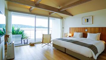 A bedroom with a large bed, a window with a view, a chair, and a potted plant.