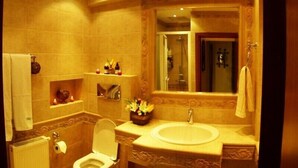A bathroom with a toilet, sink, and decorative shelves. - Villa Paradizo (Kalamata)