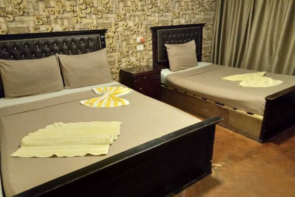 A hotel room with two beds, each with a headboard and a pillow.
