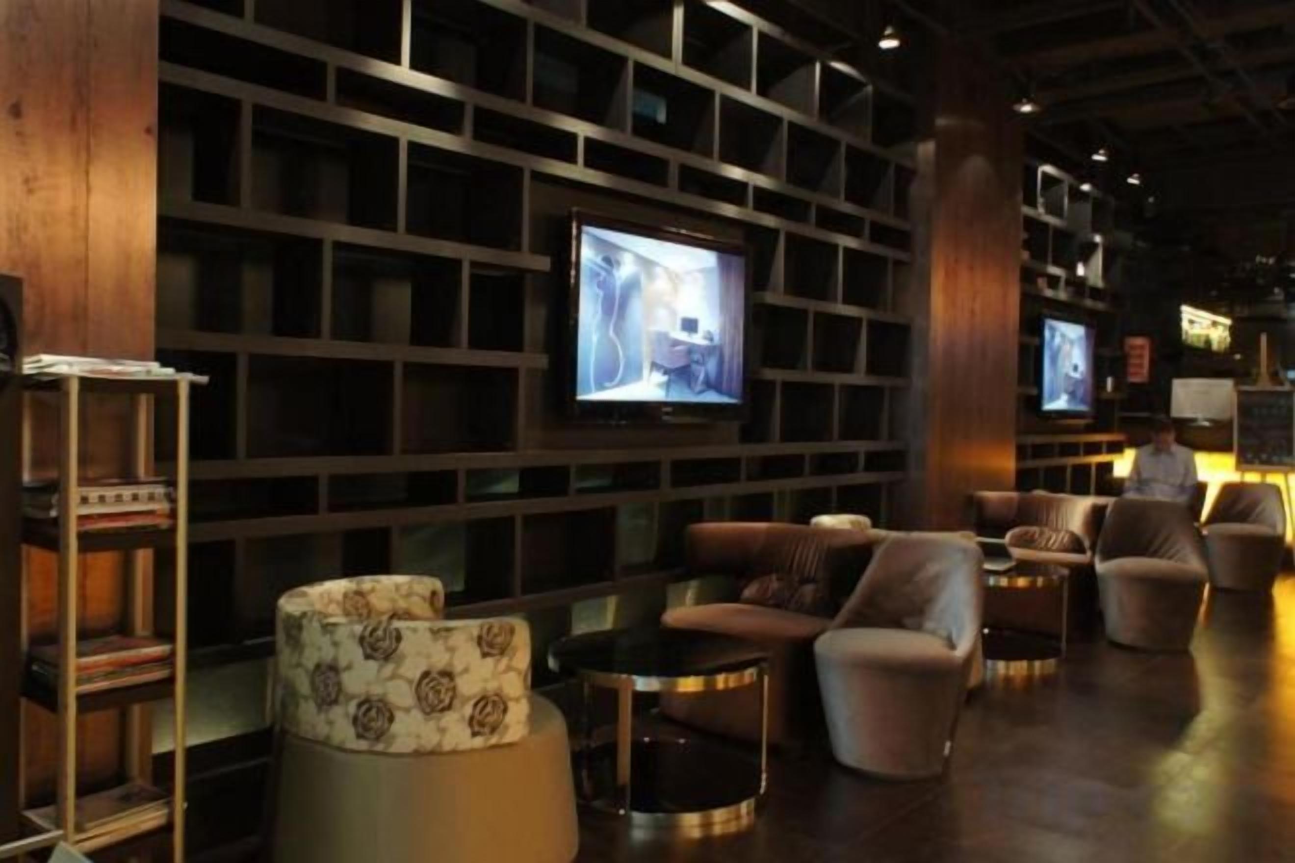 A modern lounge area with sofas, a television, and a bookshelf.