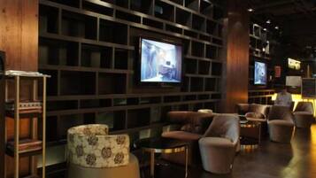 A modern lounge area with sofas, a television, and a bookshelf.