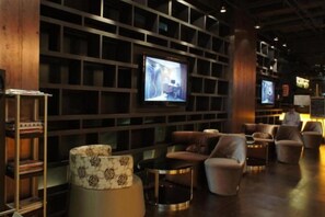A modern lounge area with sofas, a television, and a bookshelf. - Housing International Hotel (Qingdao)