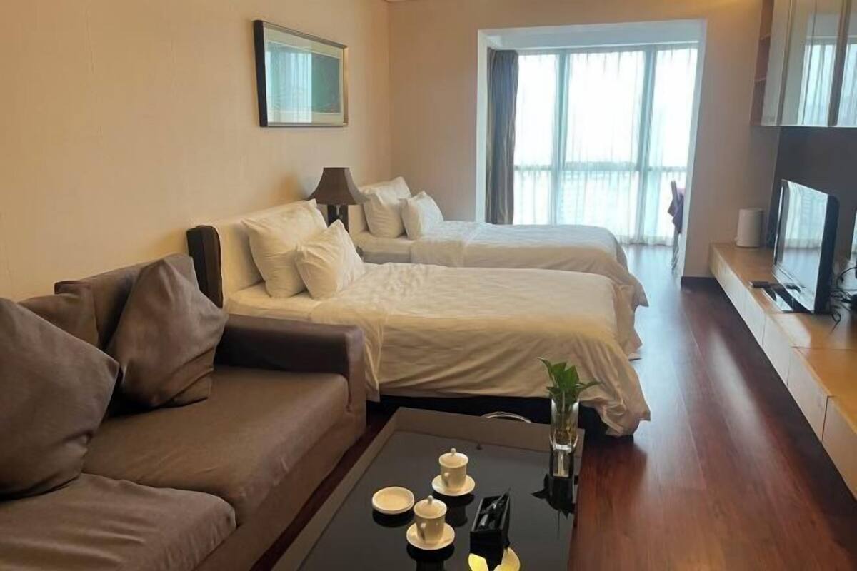 A hotel room with two beds, a sofa, a coffee table, and a TV.