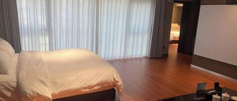 A modern hotel room with a large bed, wooden flooring, and a small table with decorative items.