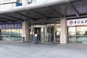 A building entrance with a revolving door, a sign for 'Worlds International English,' and another sign with Chinese characters. - Housing International Hotel (Qingdao)