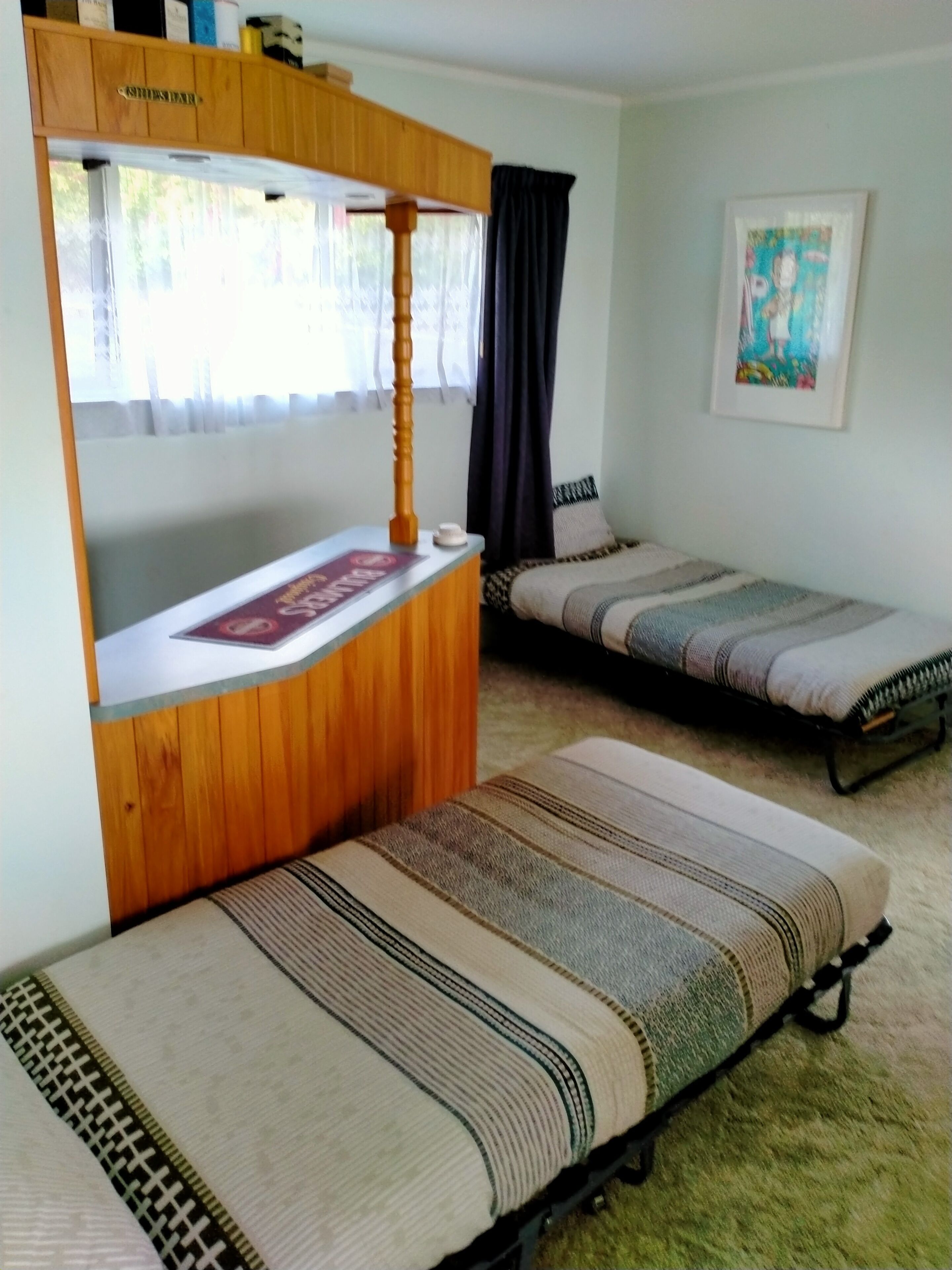 A room with two single beds, a wooden bunk bed, and a small table with a magazine.