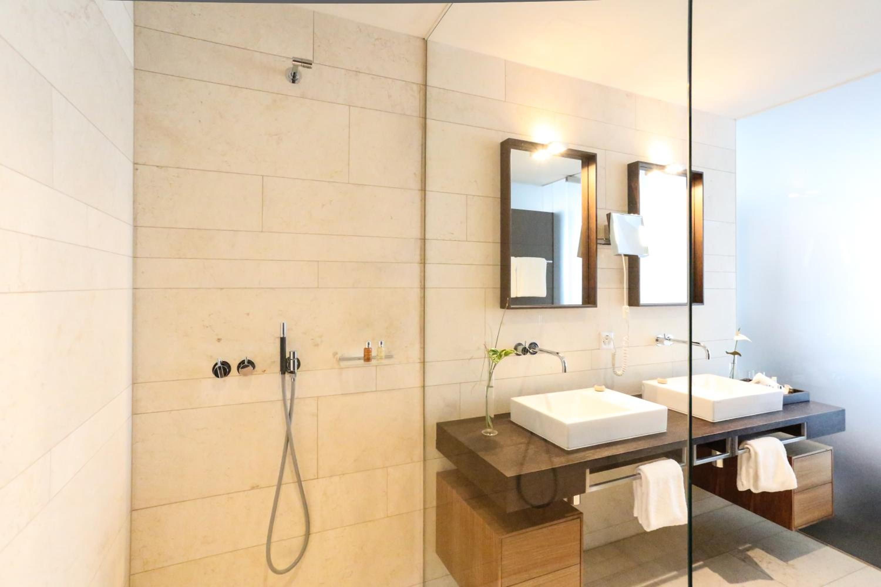 Une salle de bain moderne avec une douche à parois de verre, deux lavabos et un meuble-lavabo avec un miroir.
